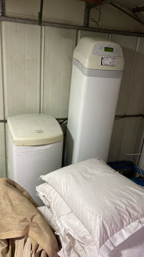 Ablandador de resina con estanque de salmuera y sacos de sal apilados al lado, ocupando media bodega